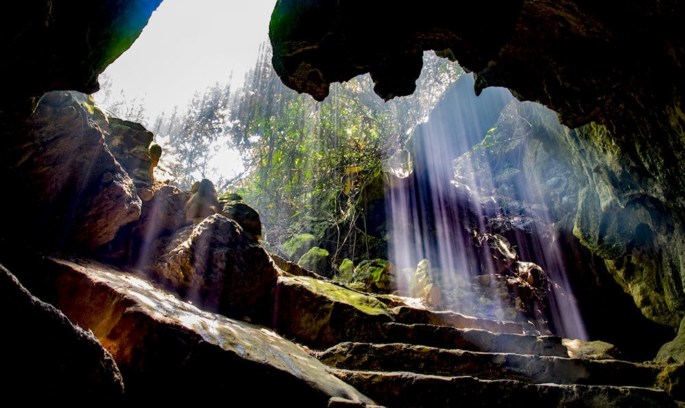 Light filtering through the cave entrance creates a shimmering celestial Milky Way underground 